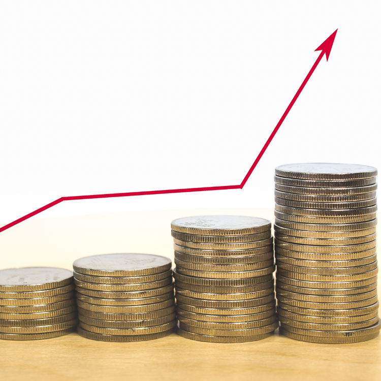 Stacked coins increasing in height with a red upward trending line graph above, symbolizing financial growth or profit.